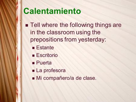 Calentamiento Tell where the following things are in the classroom using the prepositions from yesterday: Estante Escritorio Puerta La profesora Mi compañero/a.