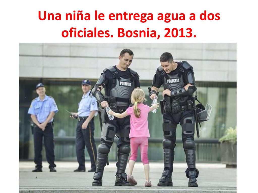 Una niña le entrega agua a dos oficiales. Bosnia, 2013.