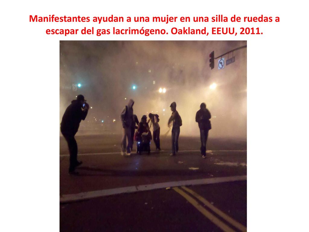 Manifestantes ayudan a una mujer en una silla de ruedas a escapar del gas lacrimógeno.