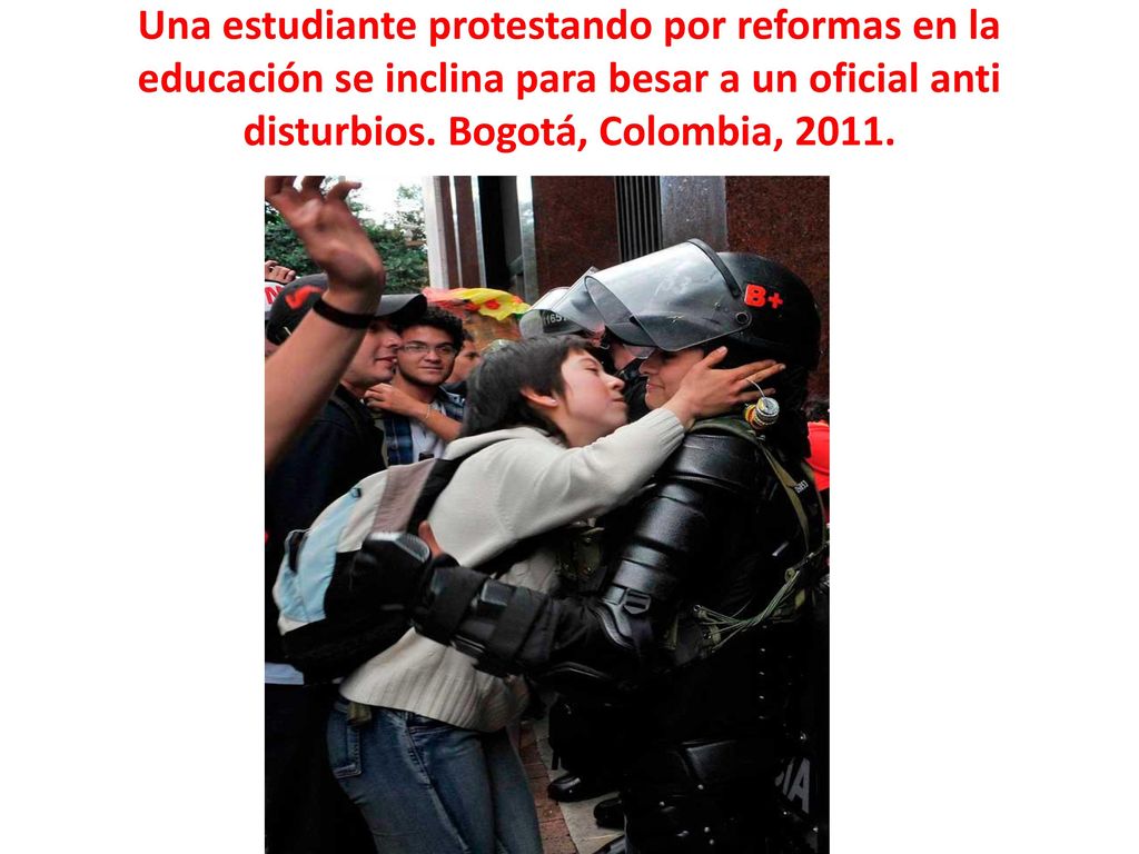 Una estudiante protestando por reformas en la educación se inclina para besar a un oficial anti disturbios.
