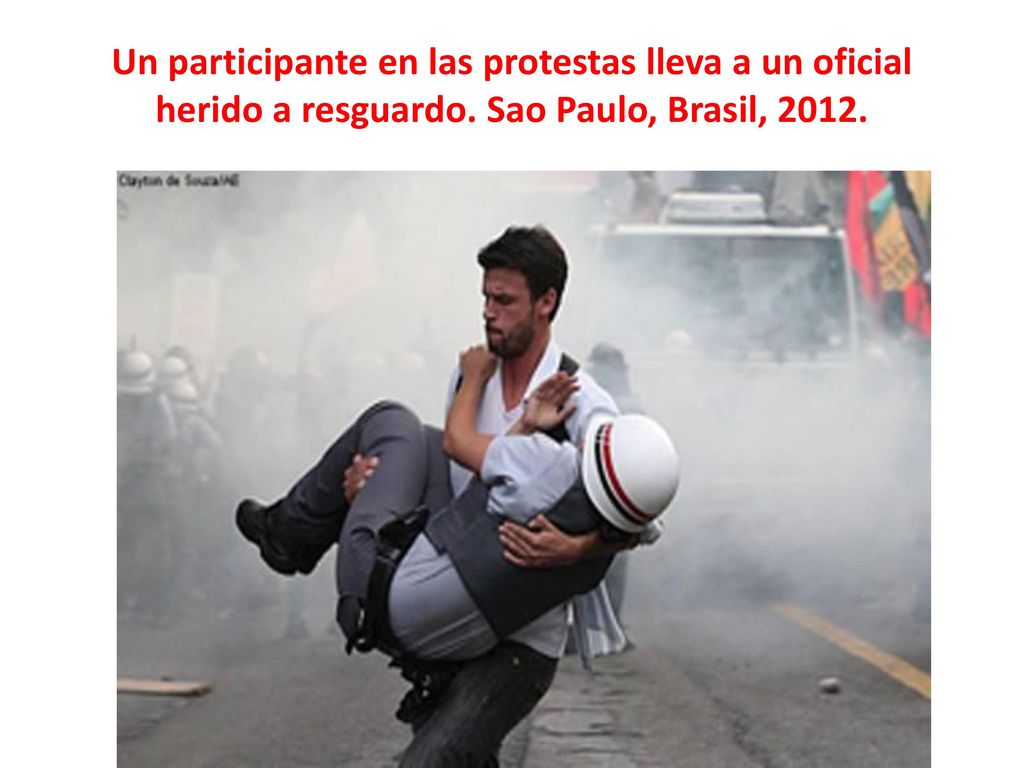 Un participante en las protestas lleva a un oficial herido a resguardo