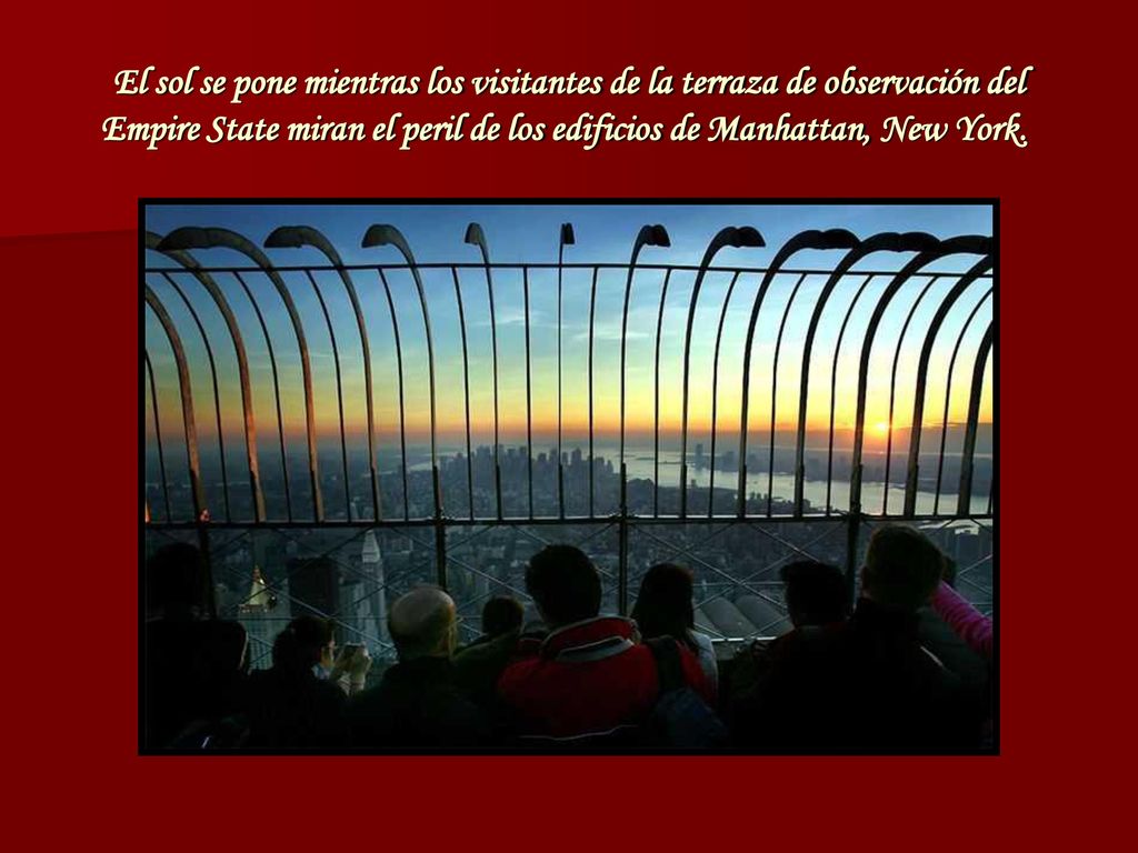 El sol se pone mientras los visitantes de la terraza de observación del Empire State miran el peril de los edificios de Manhattan, New York.