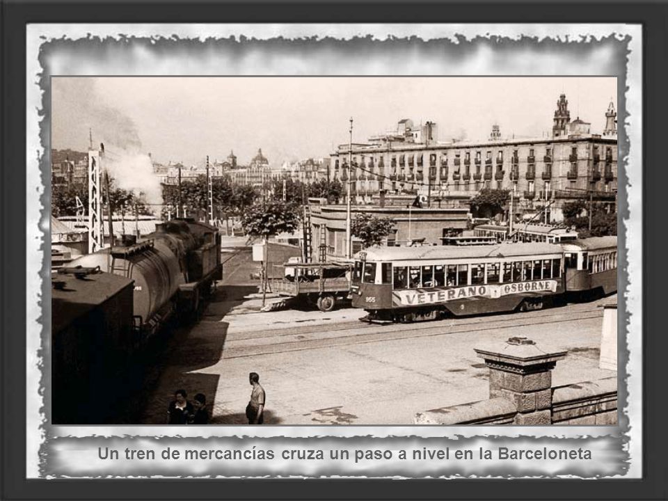 Un tren de mercancías cruza un paso a nivel en la Barceloneta