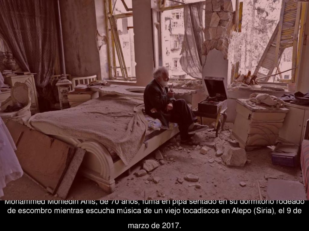 Mohammed Mohiedin Anis, de 70 años, fuma en pipa sentado en su dormitorio rodeado de escombro mientras escucha música de un viejo tocadiscos en Alepo (Siria), el 9 de marzo de 2017.