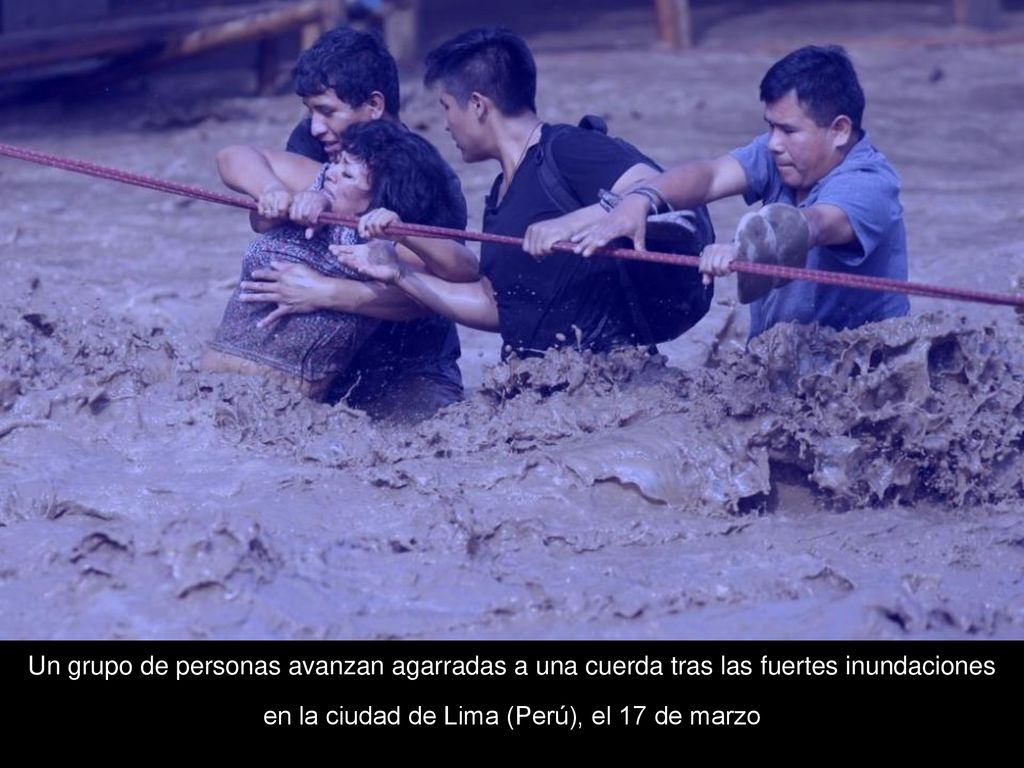 Un grupo de personas avanzan agarradas a una cuerda tras las fuertes inundaciones en la ciudad de Lima (Perú), el 17 de marzo