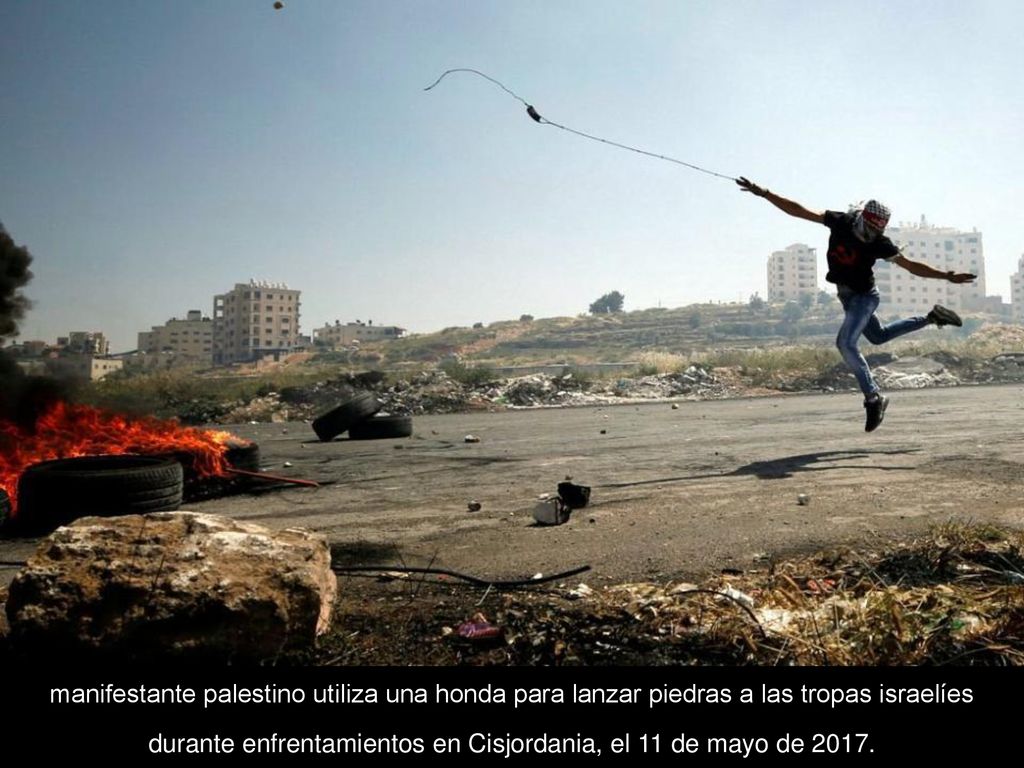 manifestante palestino utiliza una honda para lanzar piedras a las tropas israelíes durante enfrentamientos en Cisjordania, el 11 de mayo de 2017.