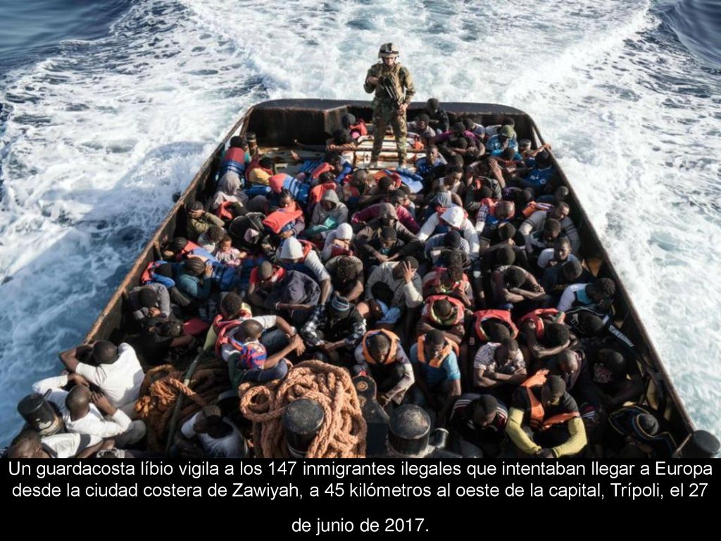 Un guardacosta líbio vigila a los 147 inmigrantes ilegales que intentaban llegar a Europa desde la ciudad costera de Zawiyah, a 45 kilómetros al oeste de la capital, Trípoli, el 27 de junio de 2017.