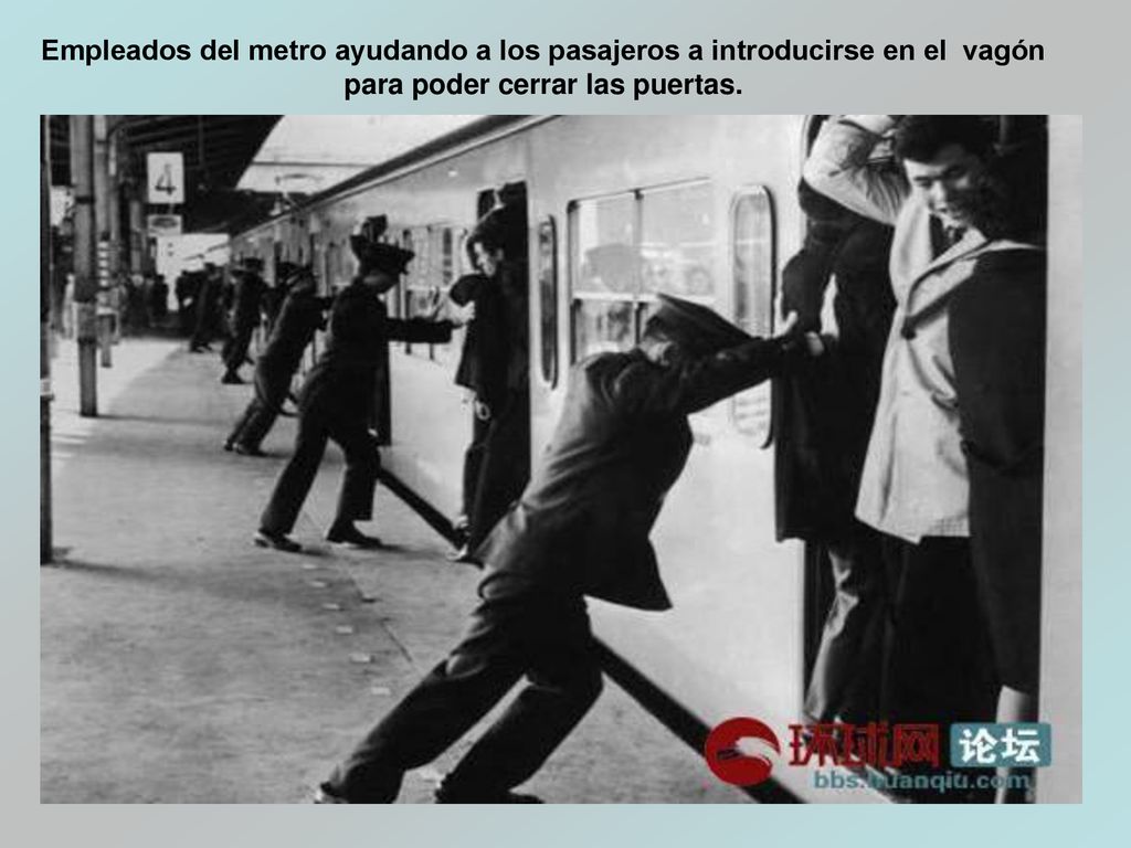 Empleados del metro ayudando a los pasajeros a introducirse en el vagón para poder cerrar las puertas.