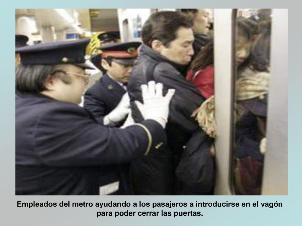 Empleados del metro ayudando a los pasajeros a introducirse en el vagón para poder cerrar las puertas.