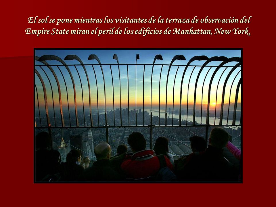 El sol se pone mientras los visitantes de la terraza de observación del Empire State miran el peril de los edificios de Manhattan, New York.