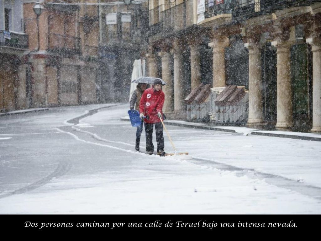 Dos personas caminan por una calle de Teruel bajo una intensa nevada.