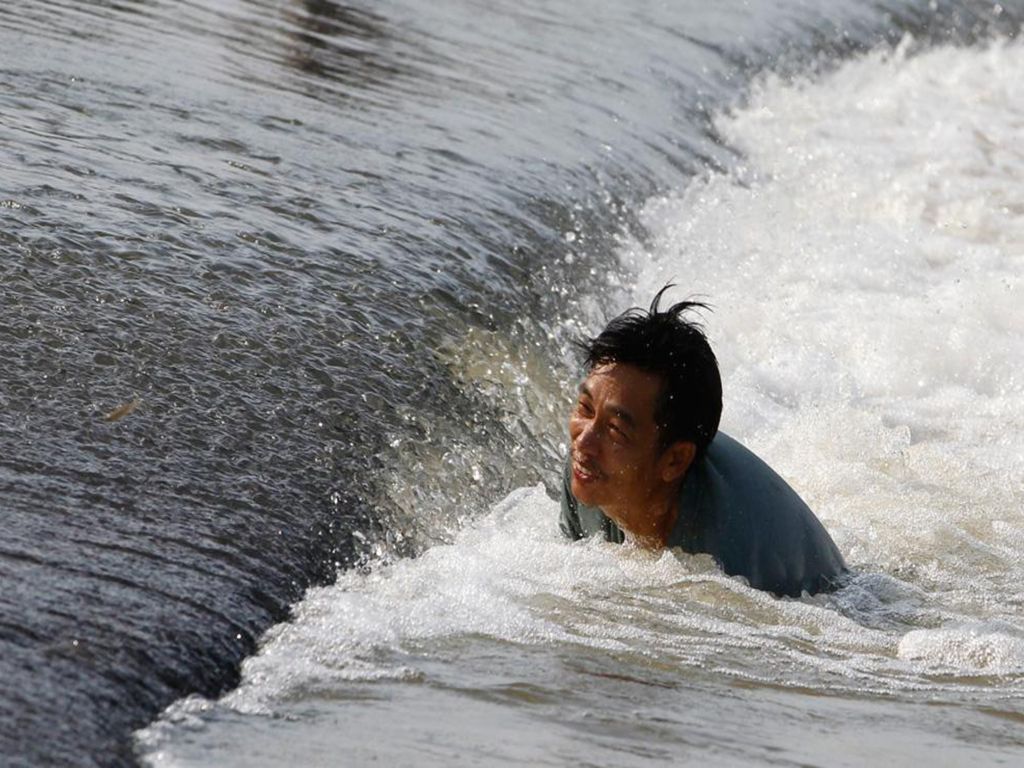A man tries to catch fish in a flooded area in Thailand s Lopburi