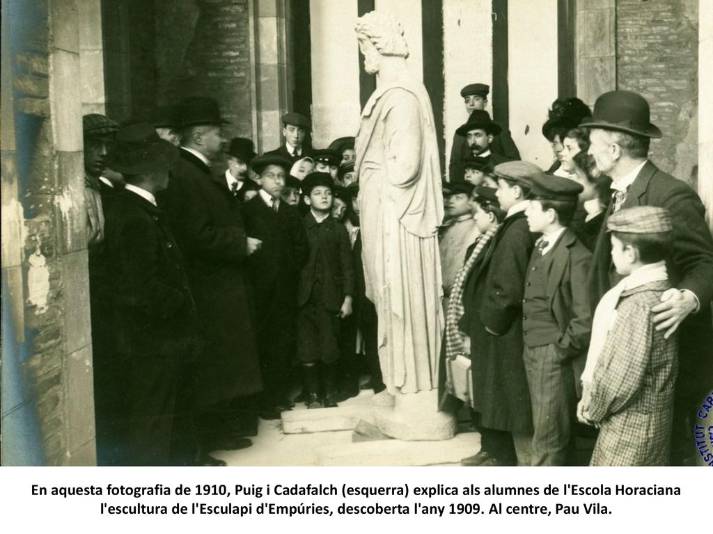 En aquesta fotografia de 1910, Puig i Cadafalch (esquerra) explica als alumnes de l Escola Horaciana l escultura de l Esculapi d Empúries, descoberta l any 1909.