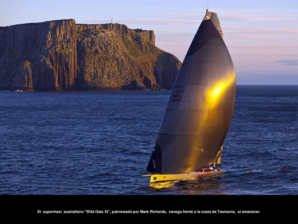 El supermaxi australiano Wild Oats XI , patroneado por Mark Richards, navega frente a la costa de Tasmania, al amanecer.