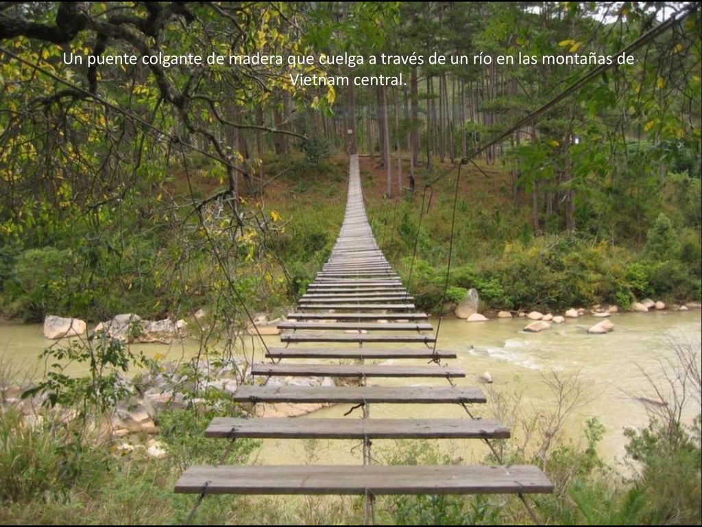 Un puente colgante de madera que cuelga a través de un río en las montañas de Vietnam central.