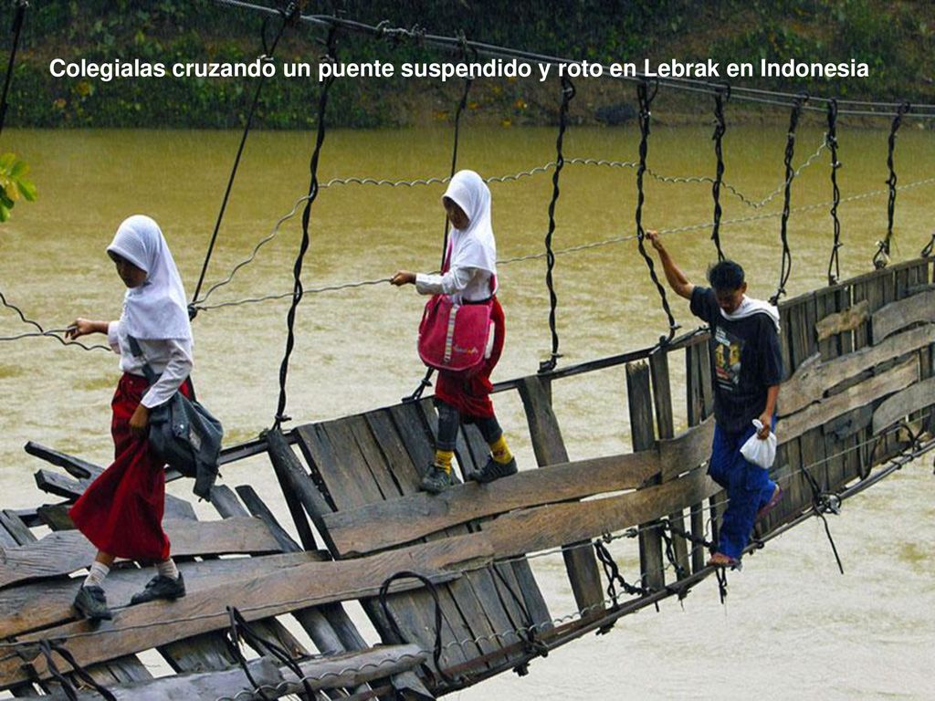 Colegialas cruzando un puente suspendido y roto en Lebrak en Indonesia