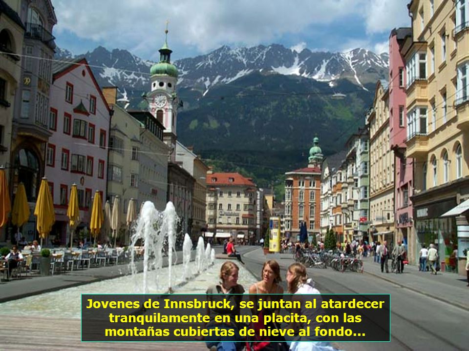 Jovenes de Innsbruck, se juntan al atardecer tranquilamente en una placita, con las montañas cubiertas de nieve al fondo...