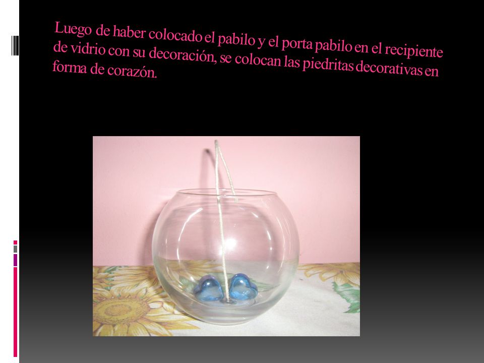 Luego de haber colocado el pabilo y el porta pabilo en el recipiente de vidrio con su decoración, se colocan las piedritas decorativas en forma de corazón.