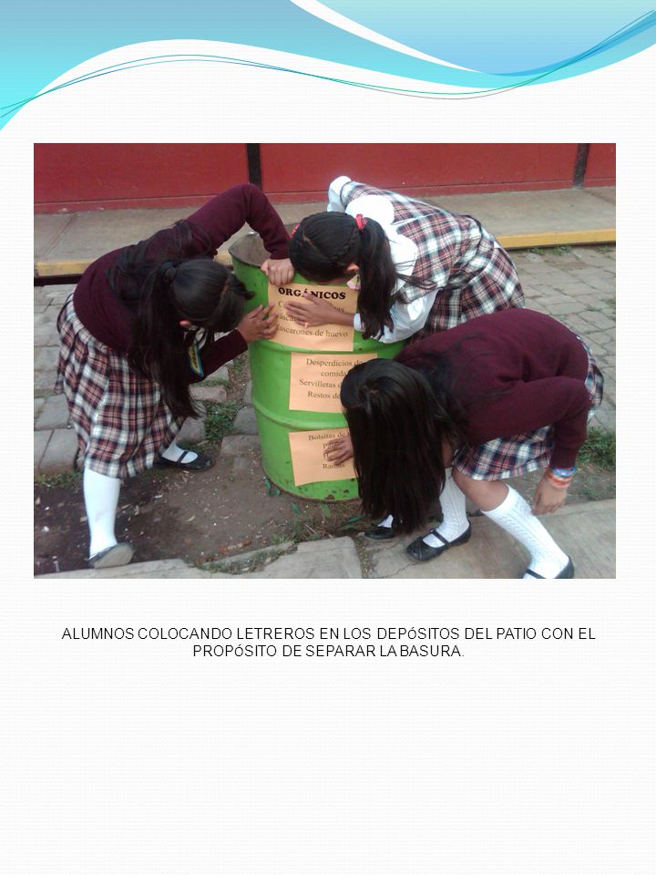 ALUMNOS COLOCANDO LETREROS EN LOS DEPÓSITOS DEL PATIO CON EL PROPÓSITO DE SEPARAR LA BASURA.