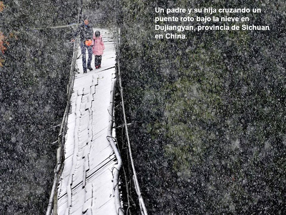 Un padre y su hija cruzando un puente roto bajo la nieve en Dujiangyan, provincia de Sichuan en China.