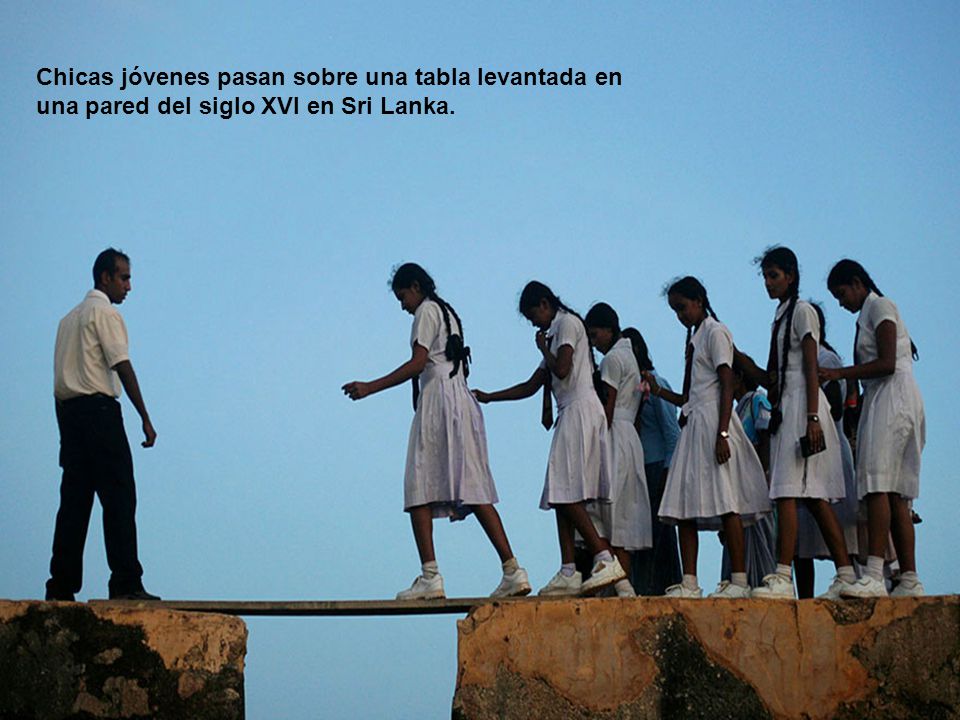 Chicas jóvenes pasan sobre una tabla levantada en una pared del siglo XVI en Sri Lanka.