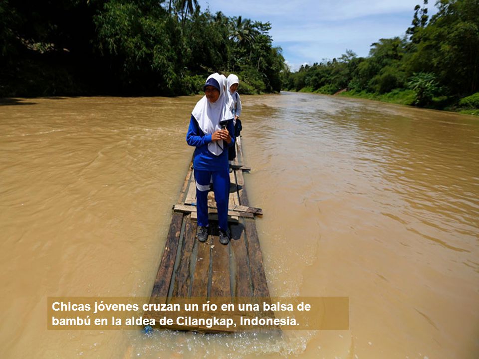 Chicas jóvenes cruzan un río en una balsa de bambú en la aldea de Cilangkap, Indonesia.