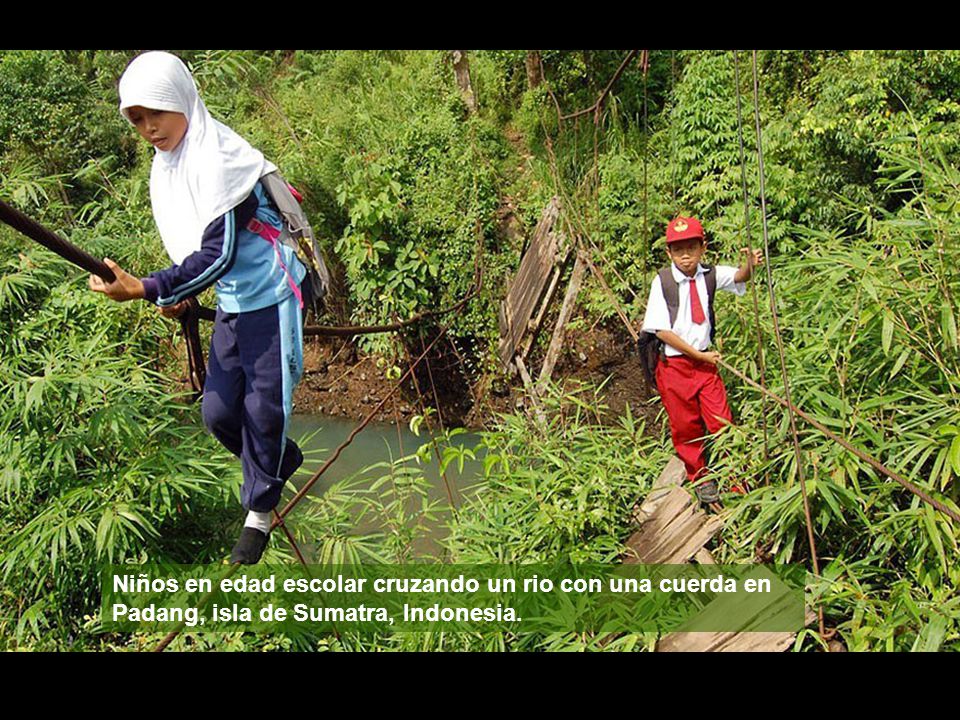 Niños en edad escolar cruzando un rio con una cuerda en Padang, isla de Sumatra, Indonesia.