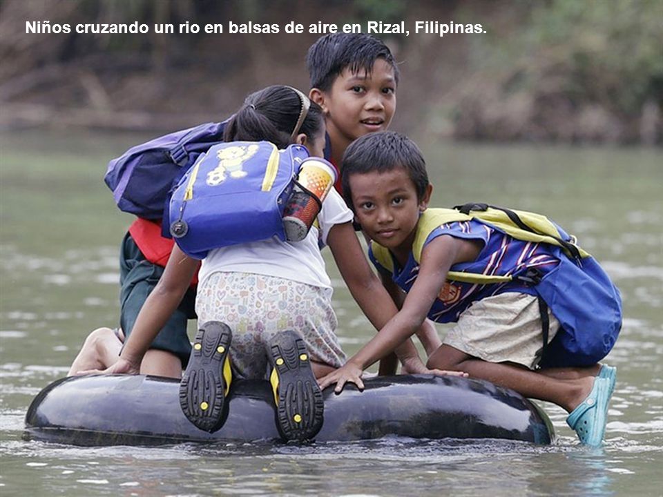 Niños cruzando un rio en balsas de aire en Rizal, Filipinas.