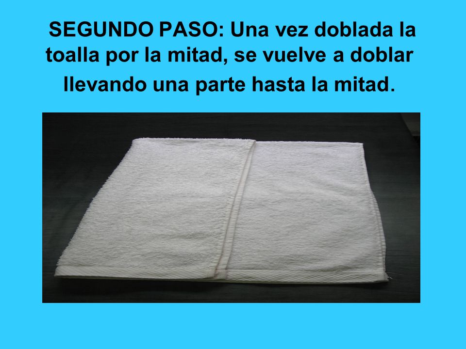 SEGUNDO PASO: Una vez doblada la toalla por la mitad, se vuelve a doblar llevando una parte hasta la mitad.