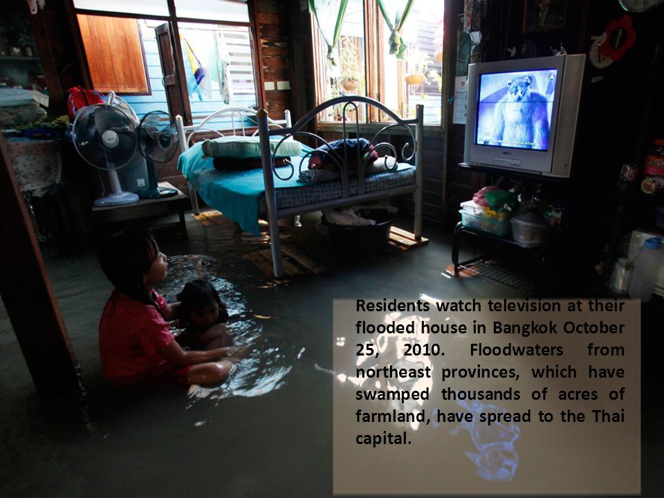 Residents watch television at their flooded house in Bangkok October 25, 2010.