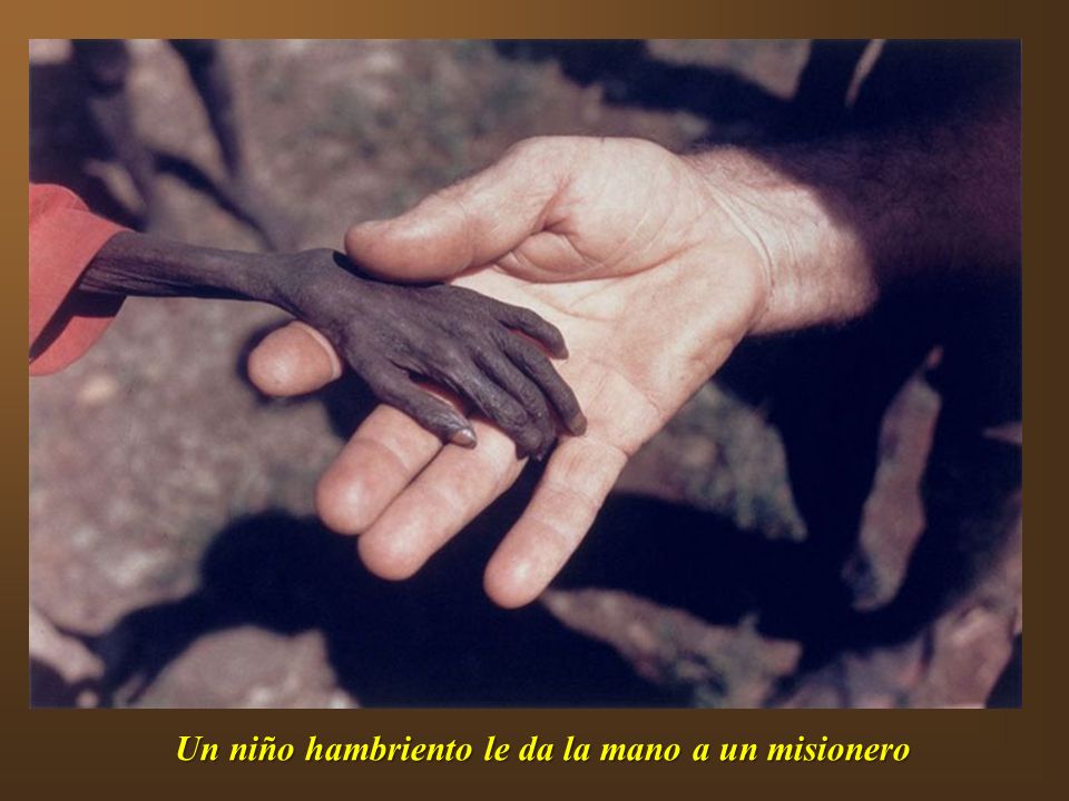 Un niño hambriento le da la mano a un misionero